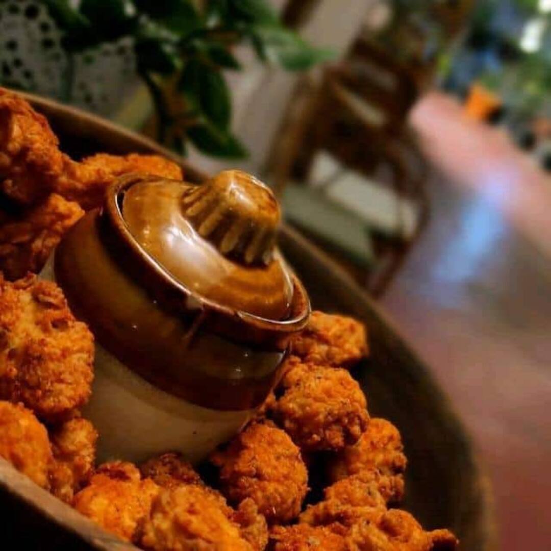 Fried appetizer bites circled on a platter with clay dip jar