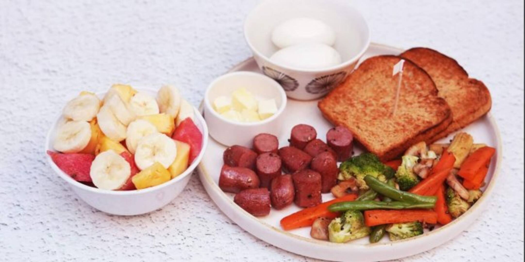 Breakfast platter with fruit, eggs, chicken sausage and toast
