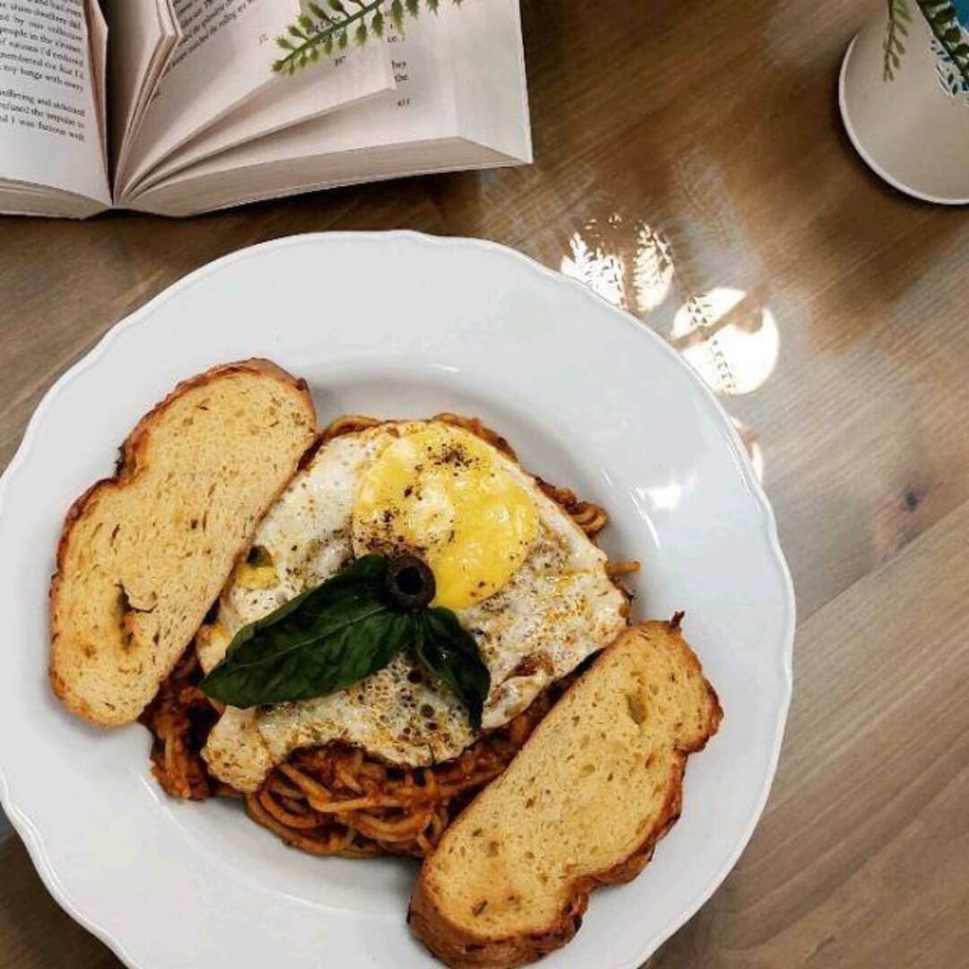 Egg-topped spaghetti on the counter, beside an open book